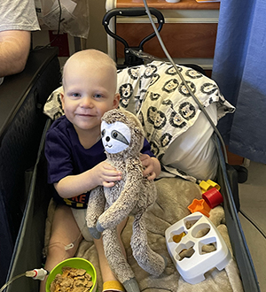 CHoR patient James Matthews holding is stuffed sloth in the hospital