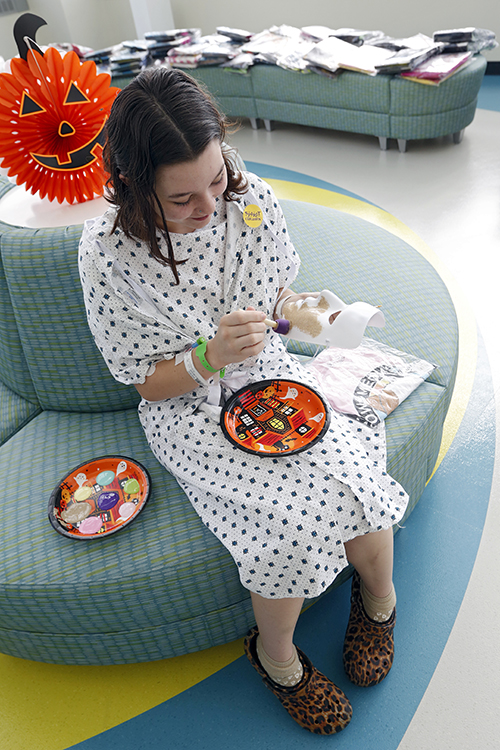 CHoR patient Myla painting a mask at the Halloween party