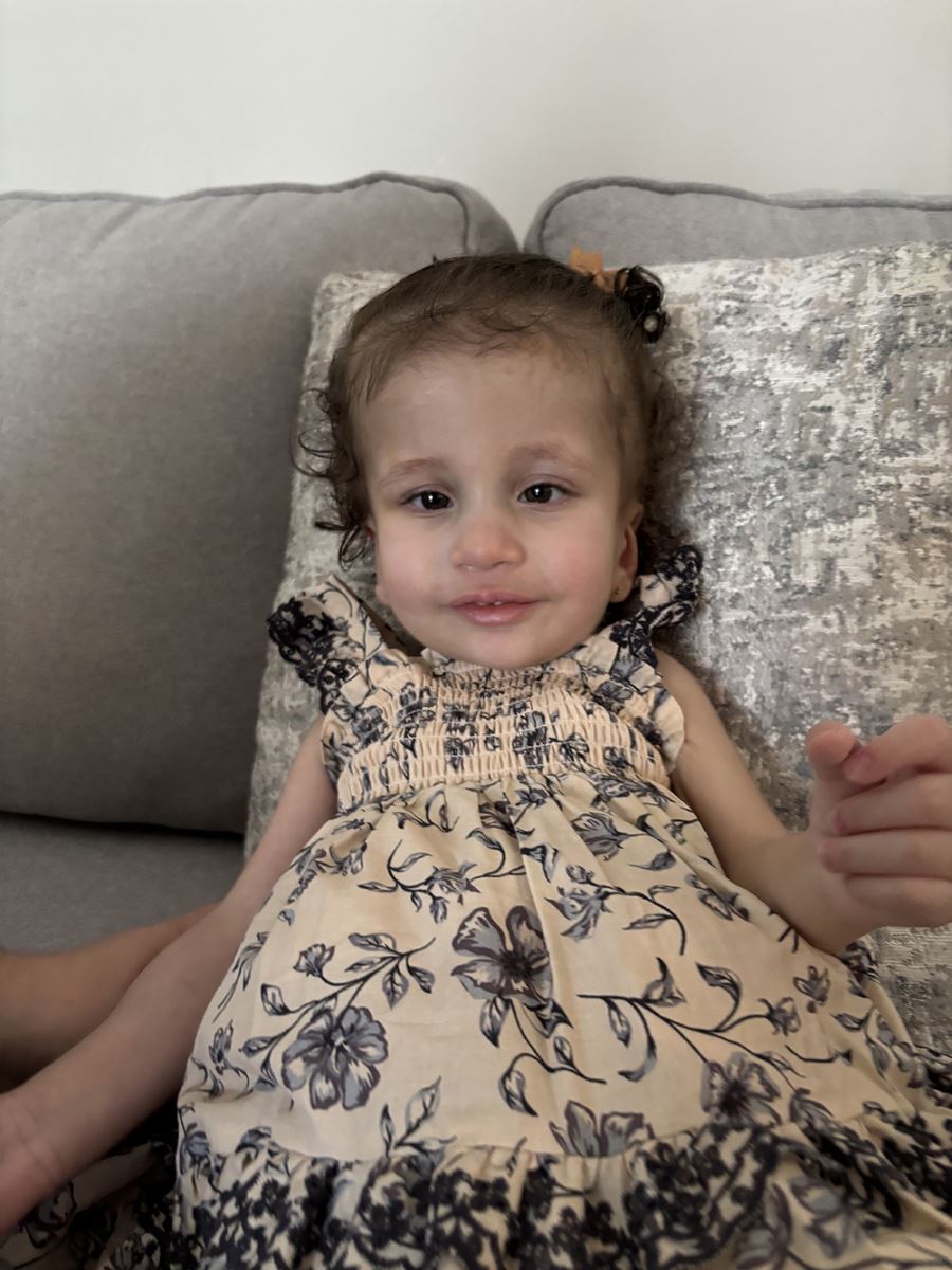 CHoR patient Alana smiling in a dress on the sofa