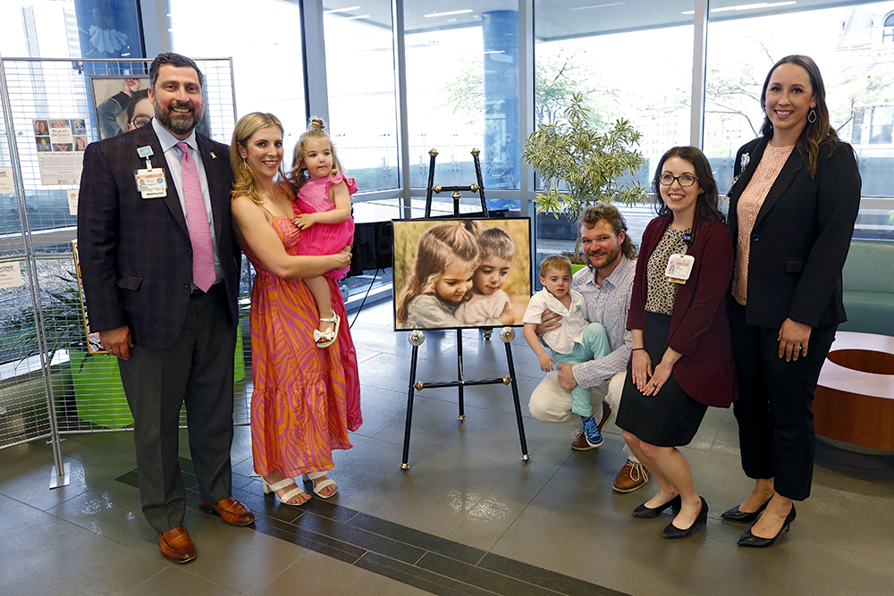 Phillips family and CHoR team members next to painting of CHoR patient Jack Phillips