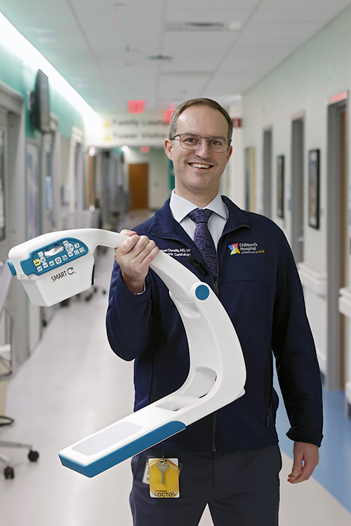 CHoR's Dr. Samuel Casella holds the mini C-Arm with one hand