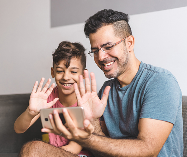 Father and son waving to phone while Facetiming