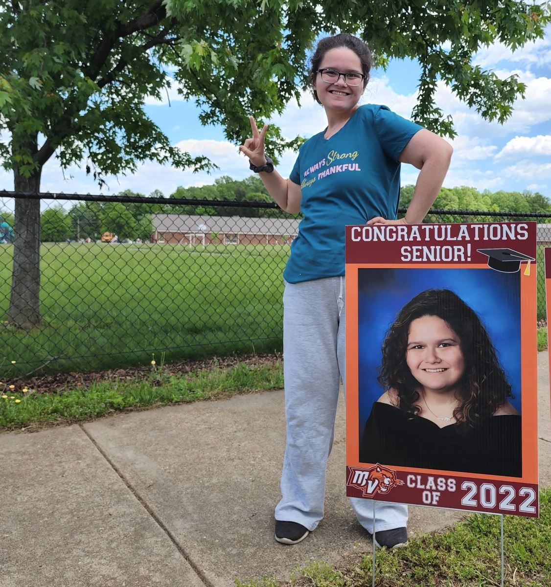 CHoR patient Bridget smiling next to her graduation sign