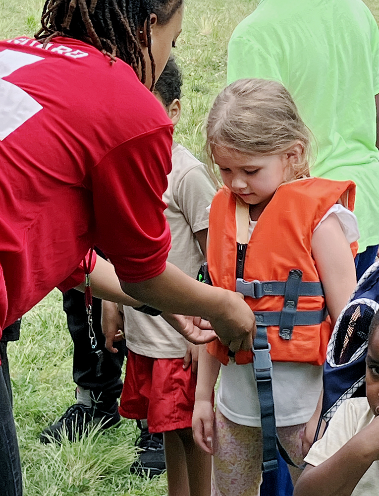 Volunteer helps show attendee how life jacket should fit