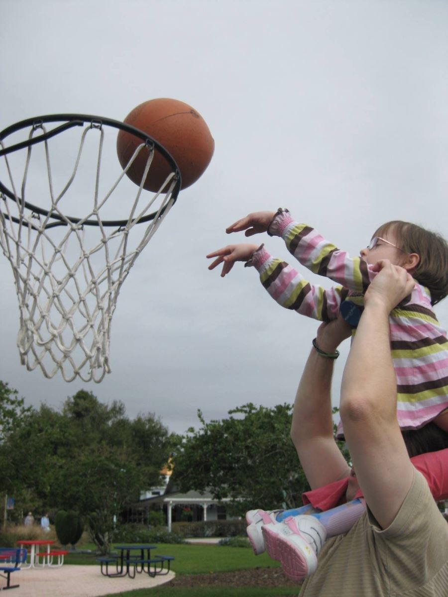 CHoR patient Hannah Smith shooting a basket from her dad's shoulders as a toddler