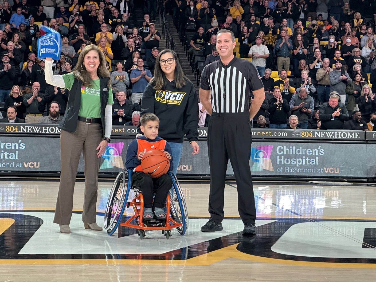 CHoR Calendar Kid Jonah presenting the game ball at the VCU basketball game
