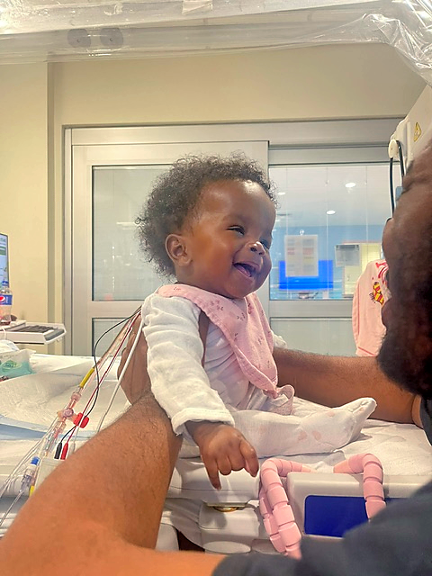 CHoR patient Kamryn smiling while dad holds her in hospital