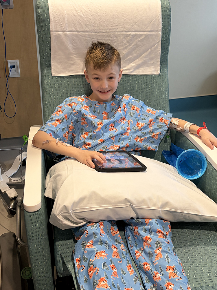 CHoR patient Keegan Bowles smiling in his hospital scrubs