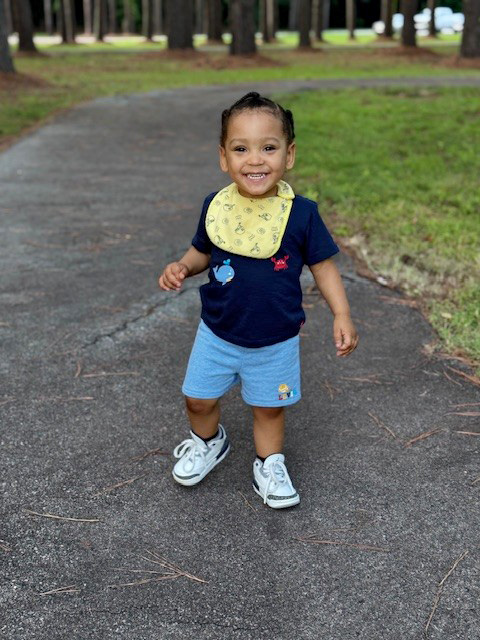 Lennox as a toddler smiling outside after care in the CHoR NICU