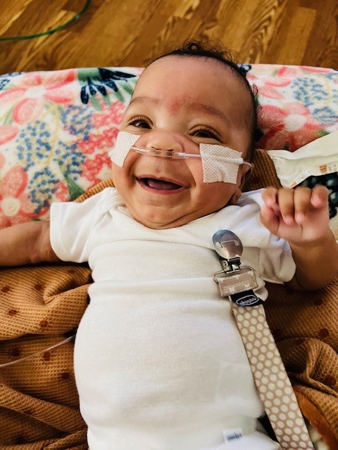 Baby Lennox smiling at home with oxygen tubes