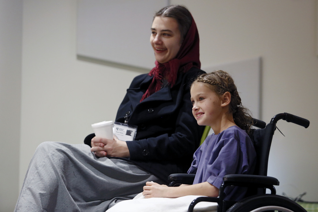 CHoR patient in wheelchair laughs with her caregiver