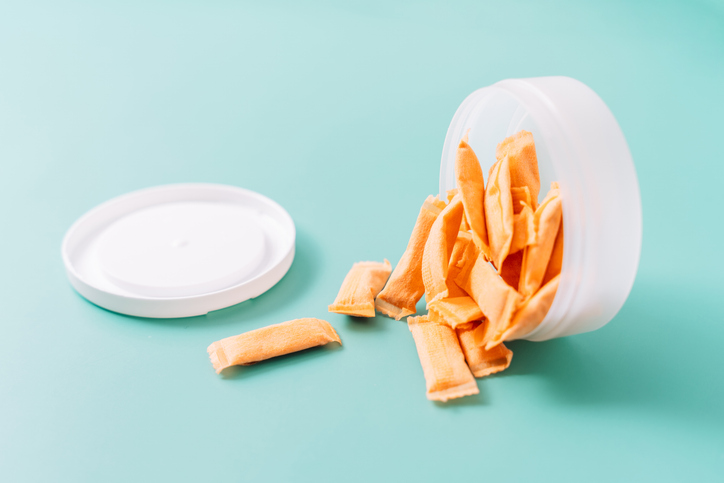 Container of orange nicotine pouches spilling open